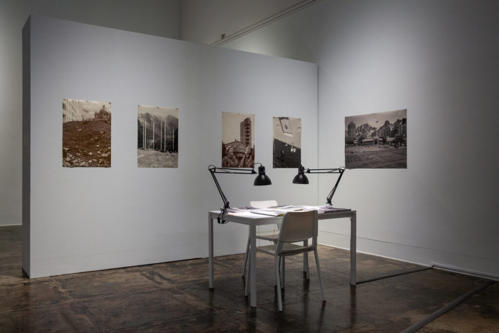 An installation with photos on the wall and a desk with lamps
