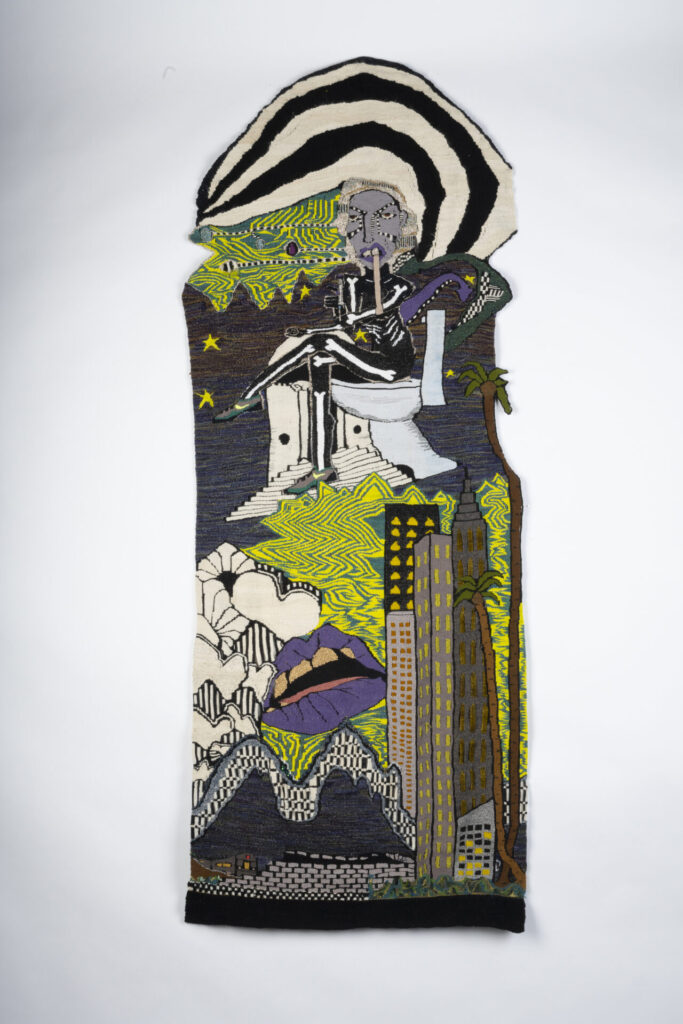 Woven tapestry with buildings and a figure.